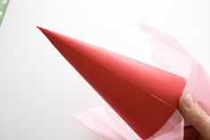 a hand is holding a red paper airplane