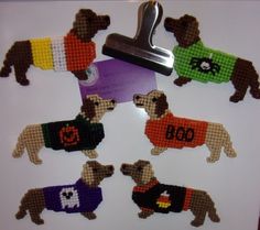 needled dogs in sweaters on a white board with a metal clip and magnet