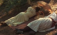 three people laying on the ground with umbrellas over their heads and one person holding an umbrella