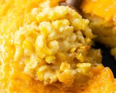 a spoon with macaroni and cheese on it is being lifted from the casserole