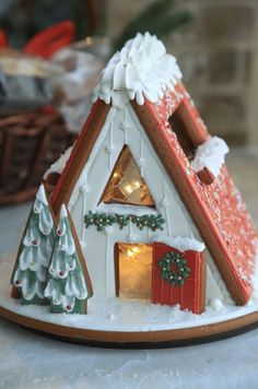 a gingerbread house decorated with christmas decorations and lights on the front, sitting on a table