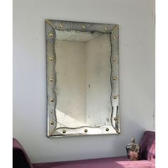 a mirror hanging on the wall above a purple couch in front of a white wall