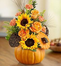 a pumpkin shaped arrangement with sunflowers and other flowers