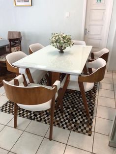 a dining room table with chairs and a vase filled with flowers on top of it