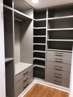 an empty walk in closet with gray and white shelves, drawers and lights on the ceiling