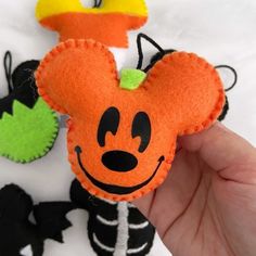 a hand is holding an orange mickey mouse brooch with black and white stripes on it