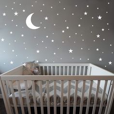 a baby's crib with white stars and moon decals on the wall