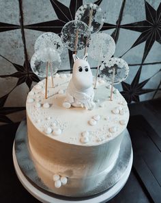 a white cake with frosting decorations and an animal figurine sitting on top