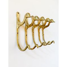 four gold metal hooks hang on a white wall