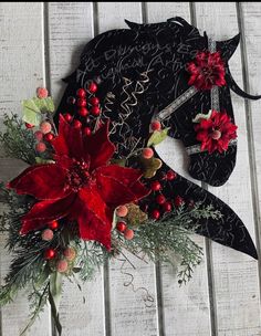 a horse's head decorated with red flowers and greenery on a white wooden background