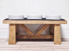 three white bowls are sitting on top of a wooden table with two black trays