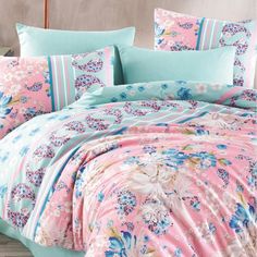 a bed covered in pink and blue comforter with flowers on it's side