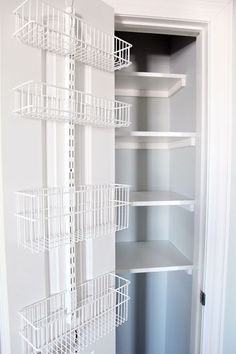 an empty closet with white shelves and wire baskets on the bottom shelf, next to a door