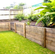 a wooden fence in the middle of a yard with green grass and plants around it