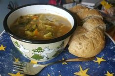 a bowl of soup next to a loaf of bread on a blue and white plate