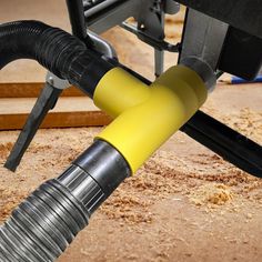 a yellow hose connected to a black and gray object on the ground next to some wood planks