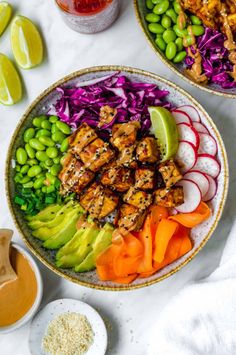 two bowls filled with meat and veggies on top of a white tablecloth