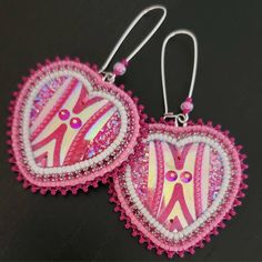 pair of pink and white heart shaped earrings on black surface with beaded edges, decorated with beads