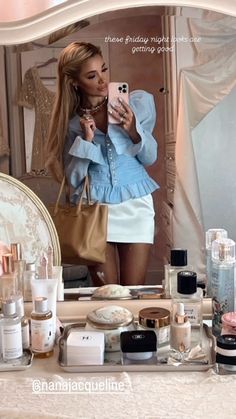 a woman taking a selfie in front of a mirror with cosmetics on the counter