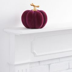 a purple pumpkin sitting on top of a white mantle