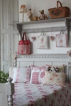 a white bed topped with lots of pillows next to a shelf filled with stuffed animals