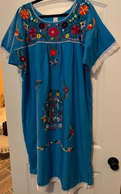 Beautiful handmade Puebla dress with bright hand embroidery from an artisan in Mexico! Dress is 80% Cotton 20% Polyester  Measurements: Chest 54" Length: 46" Care instructions: Machine wash cold Hang to dry Iron on the wrong side Dry Clean optional  Regular shipping is free, additional cost for expedited shipping! Buyer pays for return shipping and must be returned within 7 days of receipt! Seller must be notified! Traditional Light Blue Floral Embroidered Dress, Traditional Light Blue Dress With Floral Embroidery, Traditional Blue Embroidered Dress With Embroidered Hem, Traditional Blue Dress With Embroidered Hem, Traditional Light Blue Summer Dress, Blue Folk Style Embroidered Beach Dress, Folk Style Embroidered Blue Beach Dress, Folk Style Blue Embroidered Beach Dress, Folk Style Embroidered Blue Dress For Beach