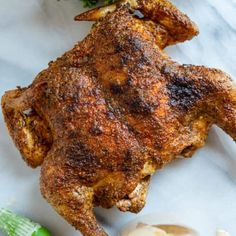 a whole chicken is sitting on a table next to some broccoli and garlic