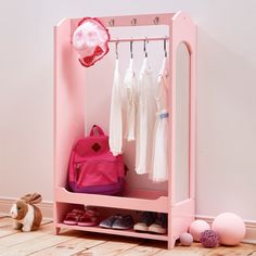 a pink toy closet with clothes, shoes and a backpack on the floor next to it