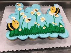 there is a cake that has been decorated to look like flowers and bees on the grass