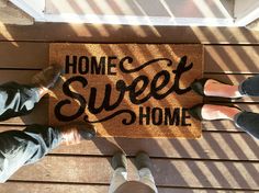 three people standing in front of a door mat that says home sweet home