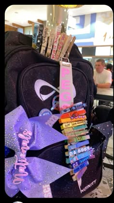 a back pack filled with school supplies and some writing on the front, along with a purple bow