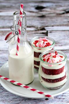 two jars filled with desserts on top of a white plate next to a bottle of milk