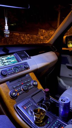 the interior of a car with an electronic device and drinks on the table in front of it