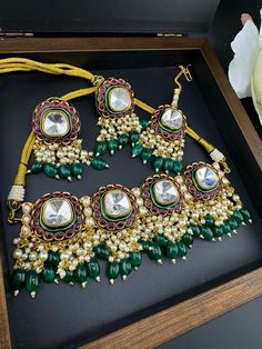 This is a trending jewelry piece This is a gorgeous modern Green and Ruby Premium quality Amrapali fusion in Pachi kundan and Italian Mina Jadau choker necklace with  moissanite Polki kundan with all natural multicolor stones and matching earrings and Tika is very unique. This is a modern style bridal set. This is so beautiful to look at and a perfect one for Bridal wear and party wear. Color : gold, Ruby and Green Necklace length :  (choker necklace length) Necklace width : 2.5 Inch Earring len Designer Green Jewelry For Gifts, Designer Green Jewelry As Gift, Designer Green Jewelry As A Gift, Designer Green Kundan Necklace With Cutdana, Green Kundan Necklace With Cutdana For Designer Wear, Designer Gold Jewelry With Meenakari, Festive Fusion Kundan Necklace, Fusion Kundan Necklace For Designer Wear, Heavy Kundan Jewelry For Designer Wear