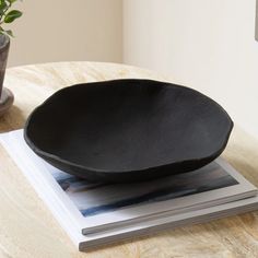 a black plate sitting on top of a table next to a potted plant