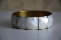 Vintage gold brass bangle inlaid with mother of pearl panels, in varying shades of white.  Perfect for stacking with other thinner bracelets Era - 80s / 90s Diameter (on inside) - 2.6 inches / 6.6 cm Height - 0.78 inches / 2 cm Condition: Very Good vintage condition. Its handmade so there are small imperfections. Mother Of Pearl Bangle Bracelets, Vintage Handmade White Cuff Bracelet, Vintage White Handmade Bangle, Handmade White Bracelets With Mother Of Pearl, Handmade White Mother Of Pearl Bracelets, Bracelets Hippie, Festival Bracelets, Hippie Bracelet, Brass Bangle