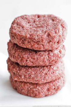 three hamburger patties stacked on top of each other in front of a white background