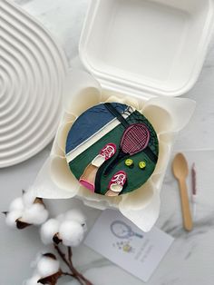 a plastic container filled with assorted items on top of a white table next to plates and utensils