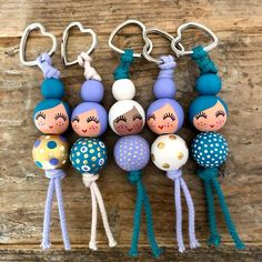 several little dolls hanging from hooks on a wooden surface