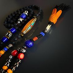 Make a bold statement with the Boho Style Tassel Necklace, a striking and unique piece of handmade jewelry that reflects your wild and free-spirited style. This handcrafted necklace features a combination of black lava rock and Evil Eye Tibetan beads, accented with colorful details and a special handmade tassel. It is not only a fashionable accessory but also a source of positive energy that can be used during yoga and meditation.The black lava rock stones are known for their grounding and calmi Bohemian Jewelry With Natural Lava Stones, Handmade Bohemian Lava Stone Jewelry, Bohemian Black Necklaces For Rituals, Spiritual Multicolor Jewelry With Black Beads, Artisan Black Necklace With 108 Beads, Bohemian Lava Stone Jewelry Gift, Bohemian Black Lava Stone Jewelry, Black Lava Stone Bohemian Jewelry, Yoga And Meditation