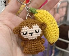 a hand holding a crocheted keychain with a small monkey on it