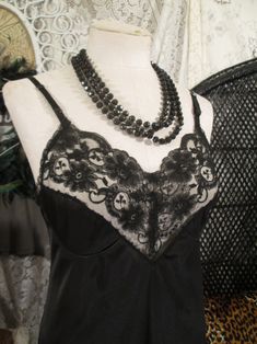 Silky black nylon satin slip with beautiful sheer lace, this vintage black slip is really lovely. The lace pattern has daisy flowers and 3 leaf clovers. Deep v neckline is sheer with princess seam cups, of lace and satin knit.  This shiny black 70s vintage slip is JC Penneys, made of Antron nylon that tries not to cling, ride up and stay silky and smooth under a dress or skirt. A  different style of Vintage Wedding lingerie.  The slip is soft all silky knit nylon. Skinny adjustable matching black 1/4" wide straps measures a 34, medium size, with a bit of stretch.  bust - 36"  waist - 31" hips - 38" full Length - 38" - 40" (adjustable) excellent condition. Machine wash and dry, gentle. the front door of the shop: www.etsy.com/shop/funkomavintage the website  -- funkomavintage.com handmade s Elegant Black Lace Camisole, Black Delicate Lace Camisole For Summer, Summer Black Lace Camisole, Sheer Lace Camisole For Party, Black Sleeveless Camisole With Lace Patchwork, Black Lace Trim Spaghetti Strap Camisole, Evening Lace V-neck Camisole, Black Delicate Lace Camisole For Night Out, Black Satin Camisole With Lace Trim