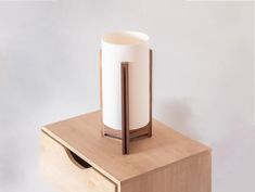 a white vase sitting on top of a wooden table next to a paper towel dispenser