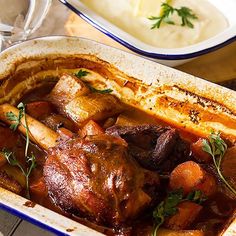 meat and potatoes in a casserole dish with gravy on the side