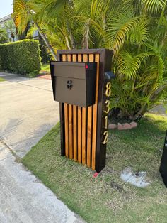 a mailbox sitting on the side of a road next to a tree and bushes