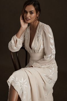 a woman in a white dress sitting on a chair