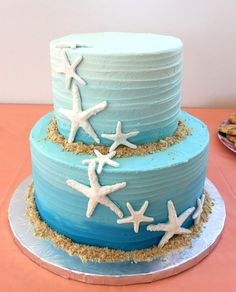 there is a blue cake with white stars on the top and sand around the edges