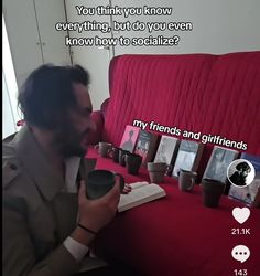 a man sitting on a red couch holding a book