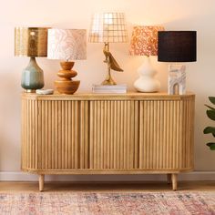 a wooden cabinet with lamps on top of it and a rug in front of it