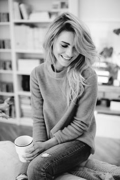 black and white photograph of a woman sitting on the floor with a coffee cup in her hand